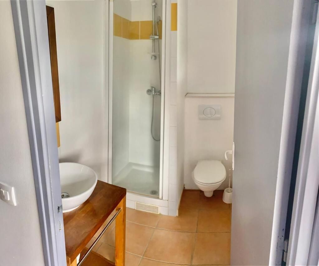 A bathroom with a glass-enclosed shower, a white sink, and a toilet.