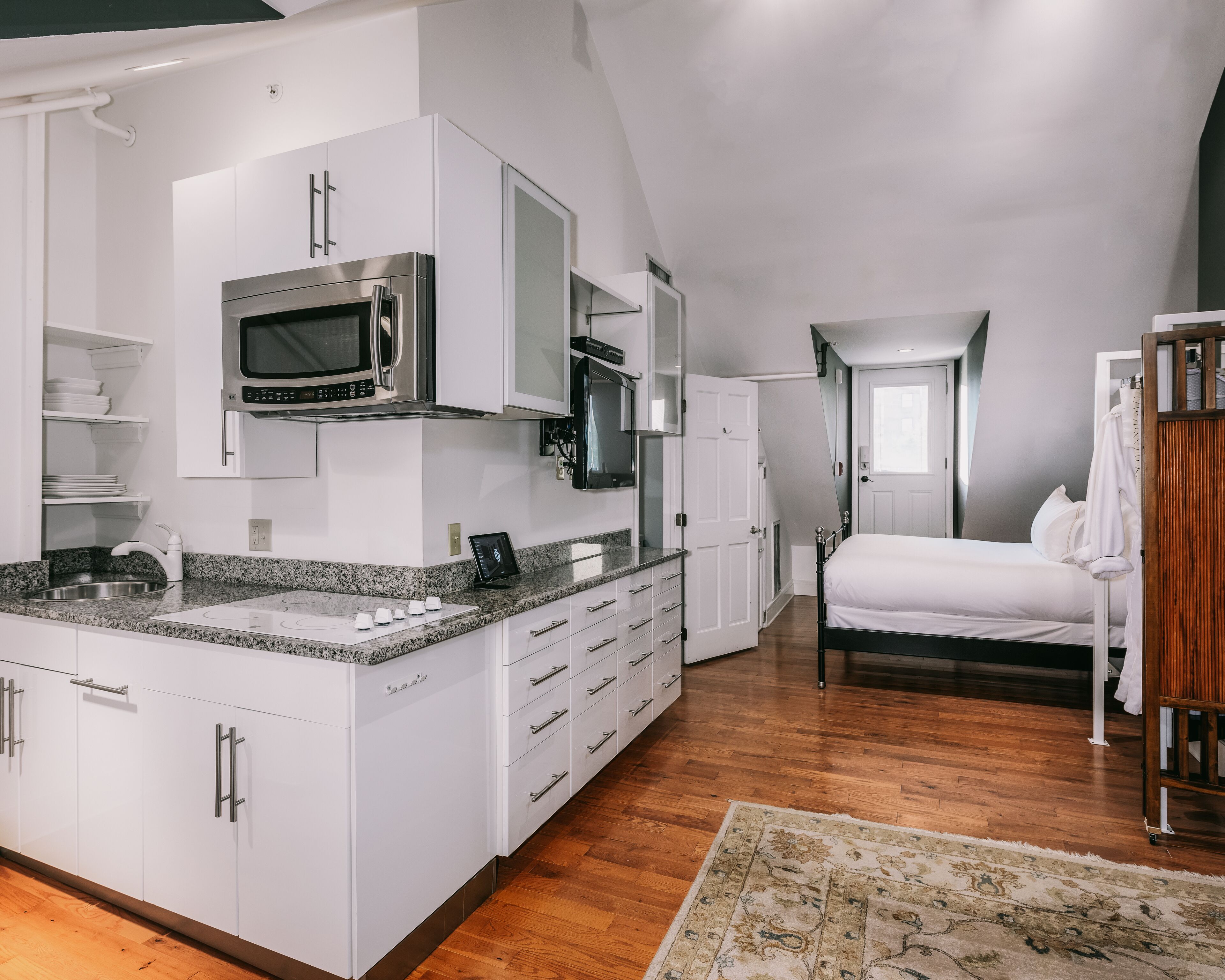Una cocina moderna con armarios blancos, encimera de granito y electrodomésticos de acero inoxidable.