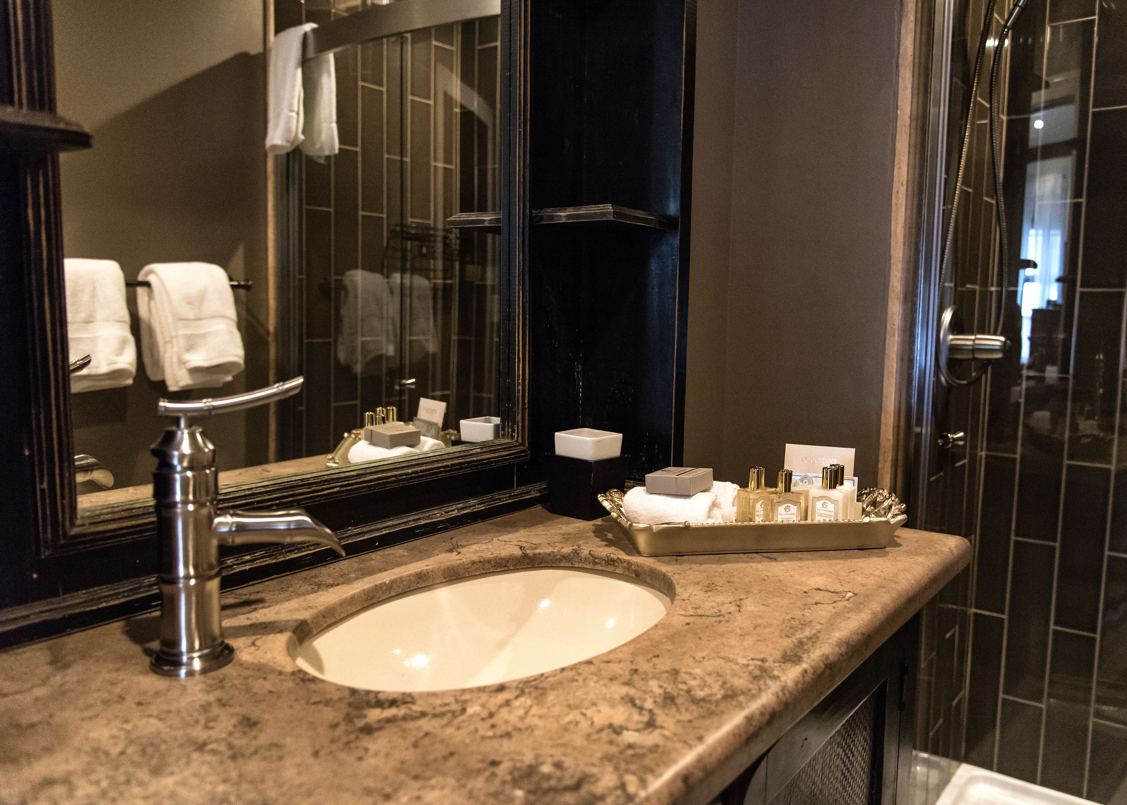 A bathroom with a sink, mirror, and toiletries.