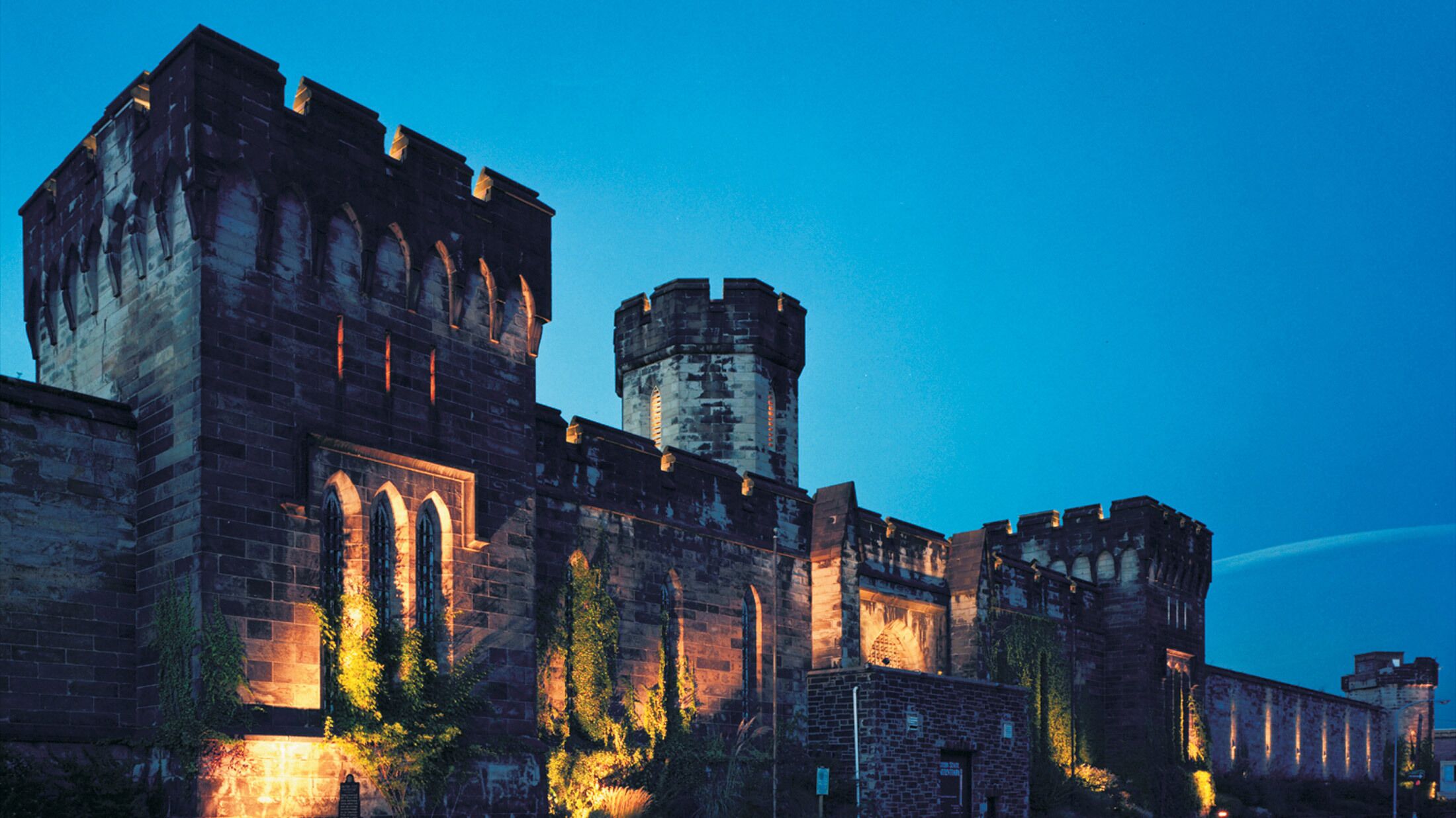 Un castillo histórico con ventanas arqueadas y una torre central, rodeado de muros y un foso.