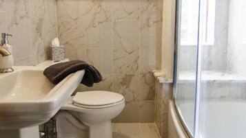 Une salle de bain comprenant des toilettes, un lavabo et un espace douche.