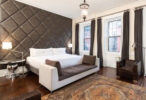 Une chambre moderne avec un grand lit, un canapé, un fauteuil et un tapis à motifs.