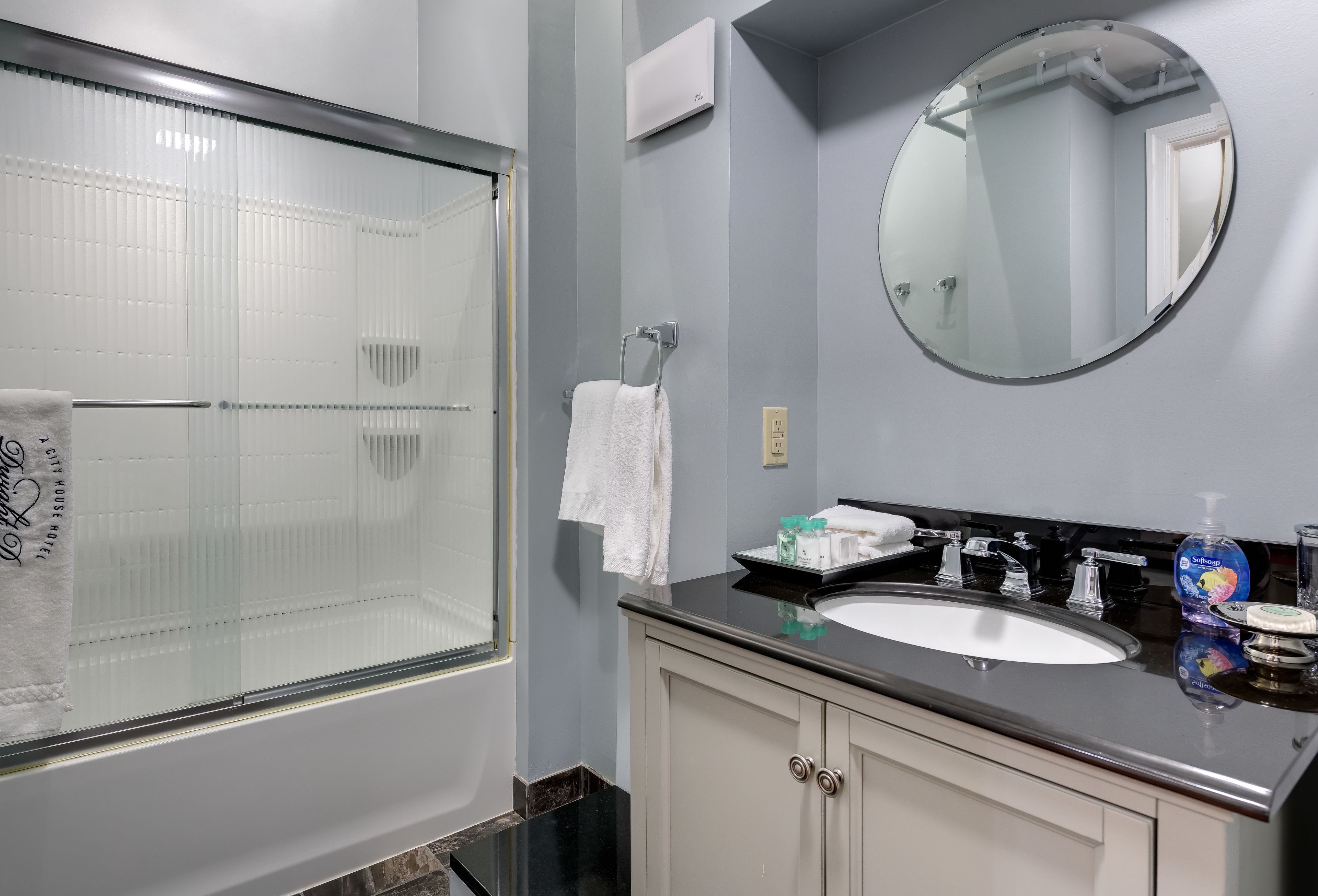 A bathroom with a glass shower enclosure, a sink with a mirror above it, and a towel hanging on a rack.