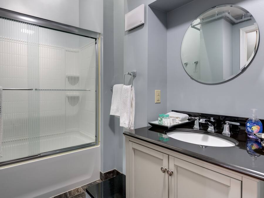 Une salle de bain avec une douche à parois de verre, un lavabo avec un miroir au-dessus et une serviette suspendue à un porte-serviettes.