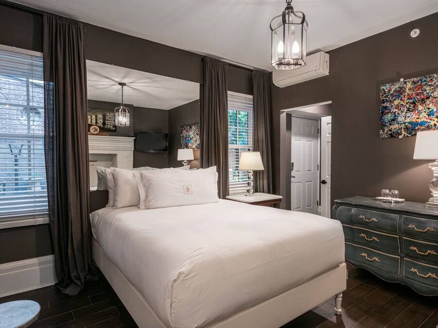 A modern hotel room with a large bed, a dresser, a television, and a painting on the wall.