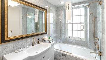 A bathroom with a large mirror, a sink, a bathtub, and a shower.