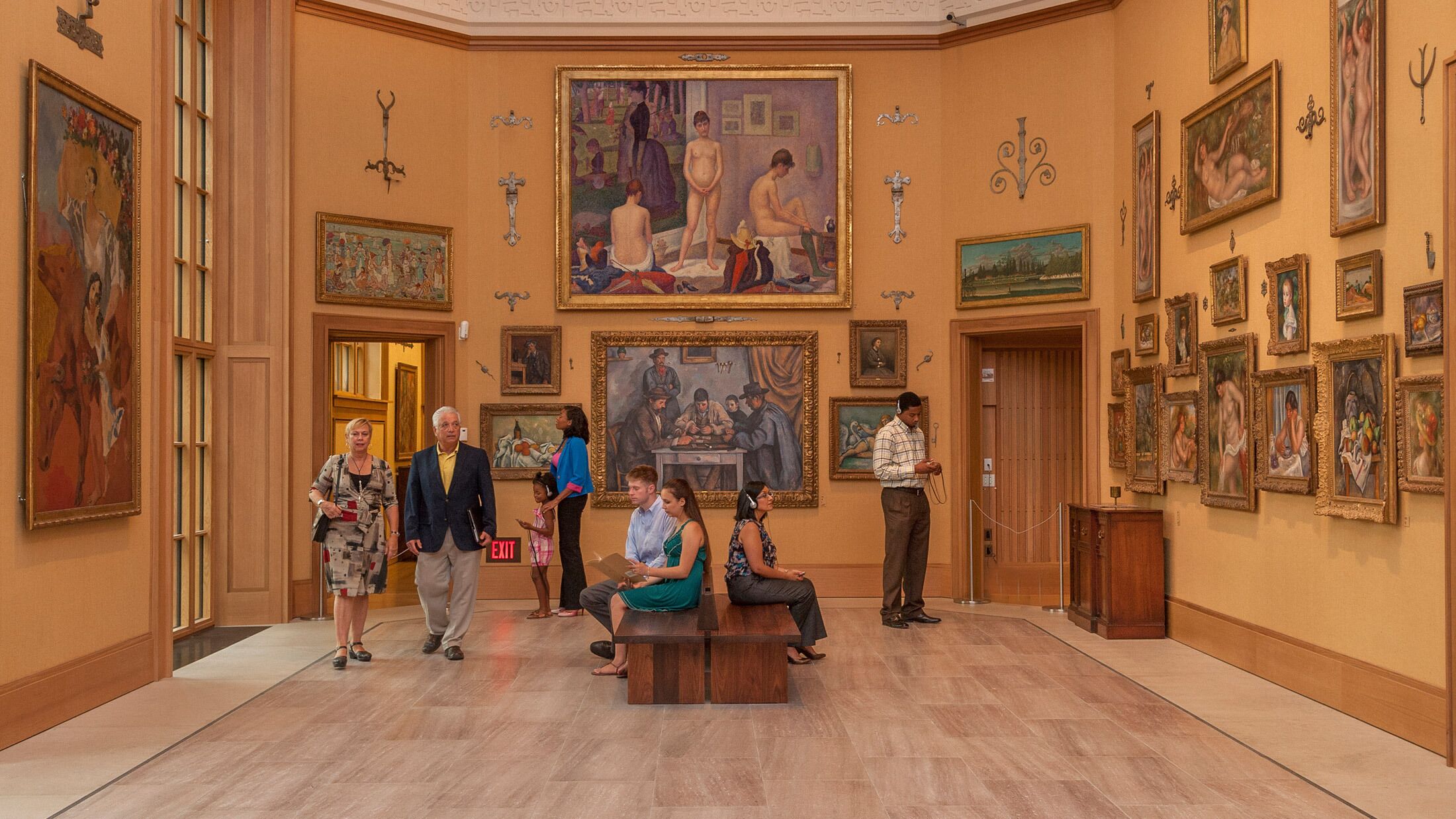 Une galerie spacieuse aux hauts plafonds et à l’architecture classique, où l’on peut admirer une variété d’œuvres d’art encadrées qui ornent les murs.