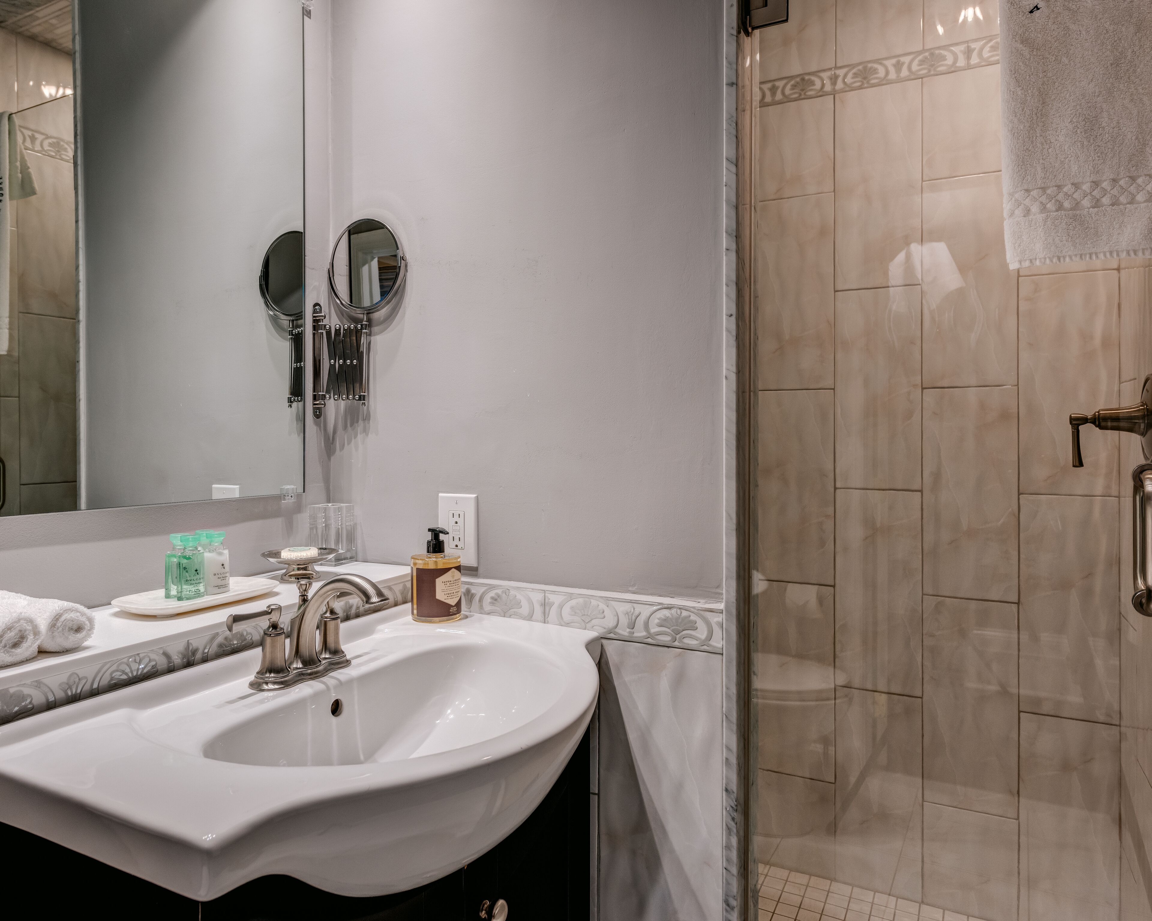 Une salle de bain avec un grand lavabo, un miroir et un espace douche.
