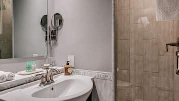 Une salle de bain avec un grand lavabo, un miroir et un espace douche.