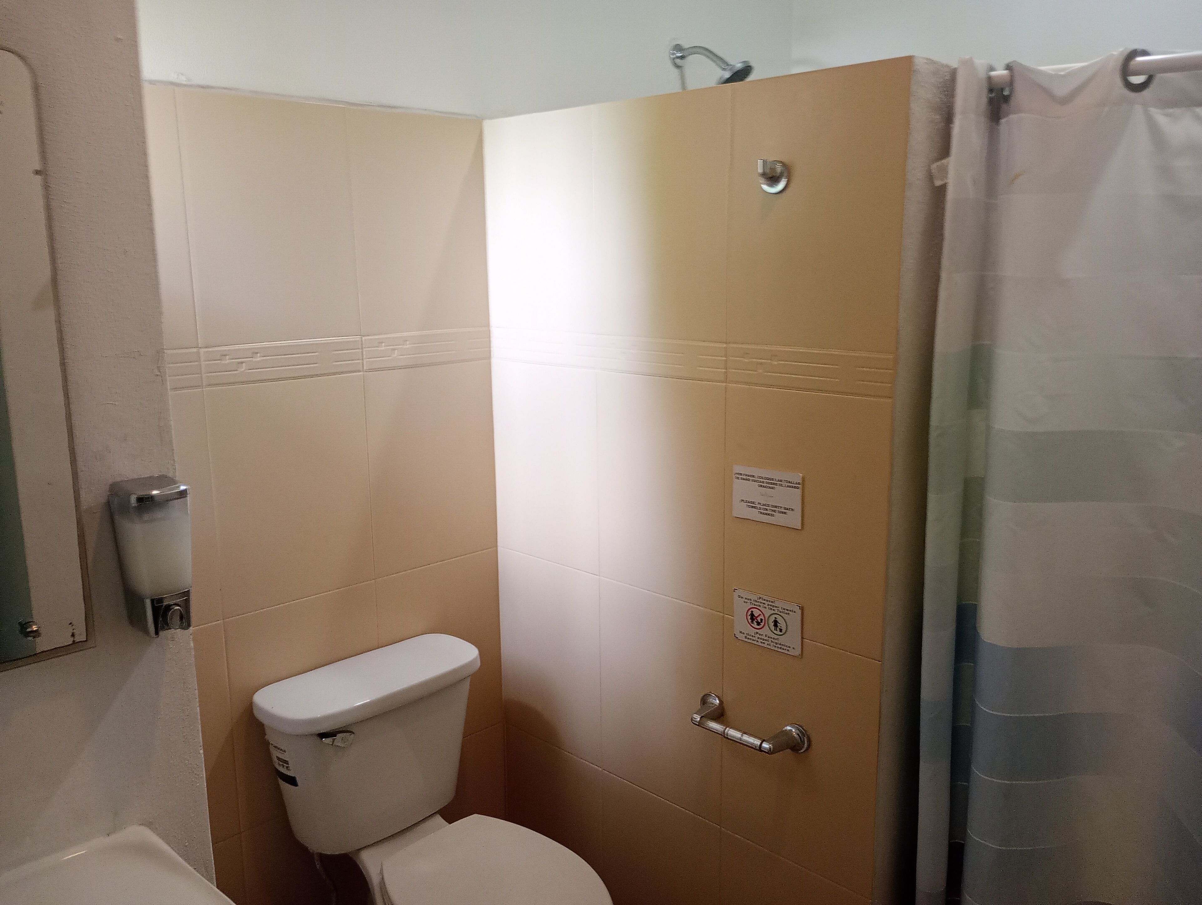A bathroom with a toilet, a shower, and a hand dryer.