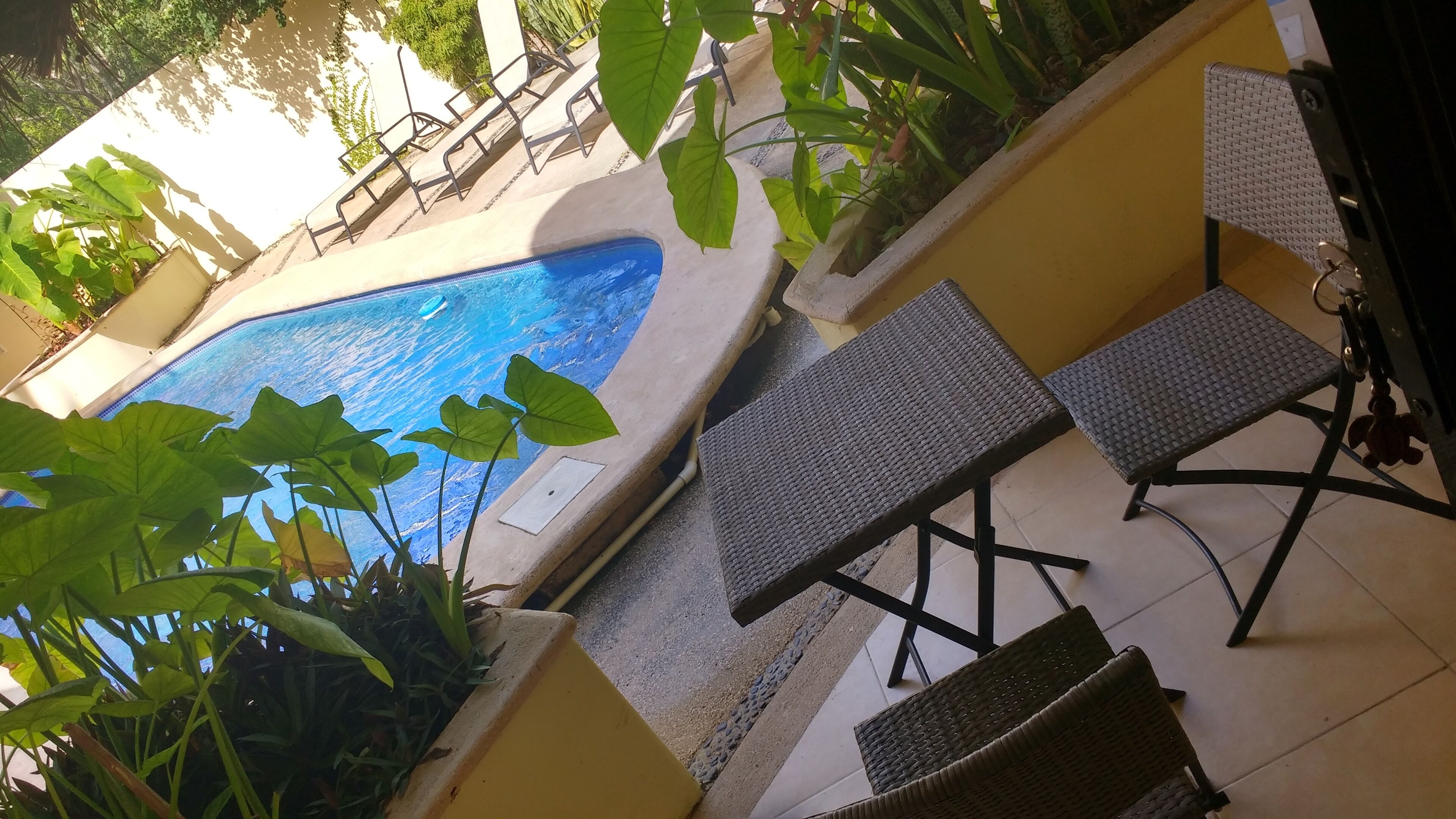 Uma área de piscina com espreguiçadeiras e um pequeno barco inflável.