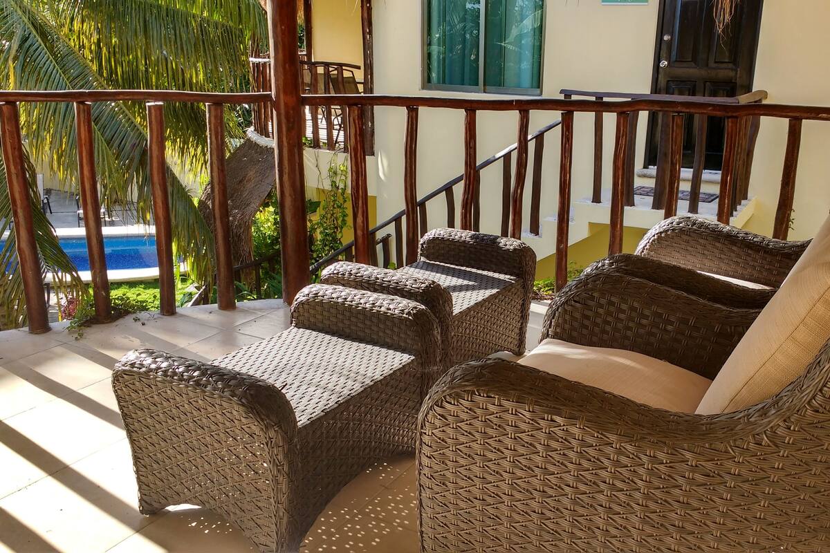 Ein Balkon mit Korbmöbeln, einem Pool und einer Treppe.