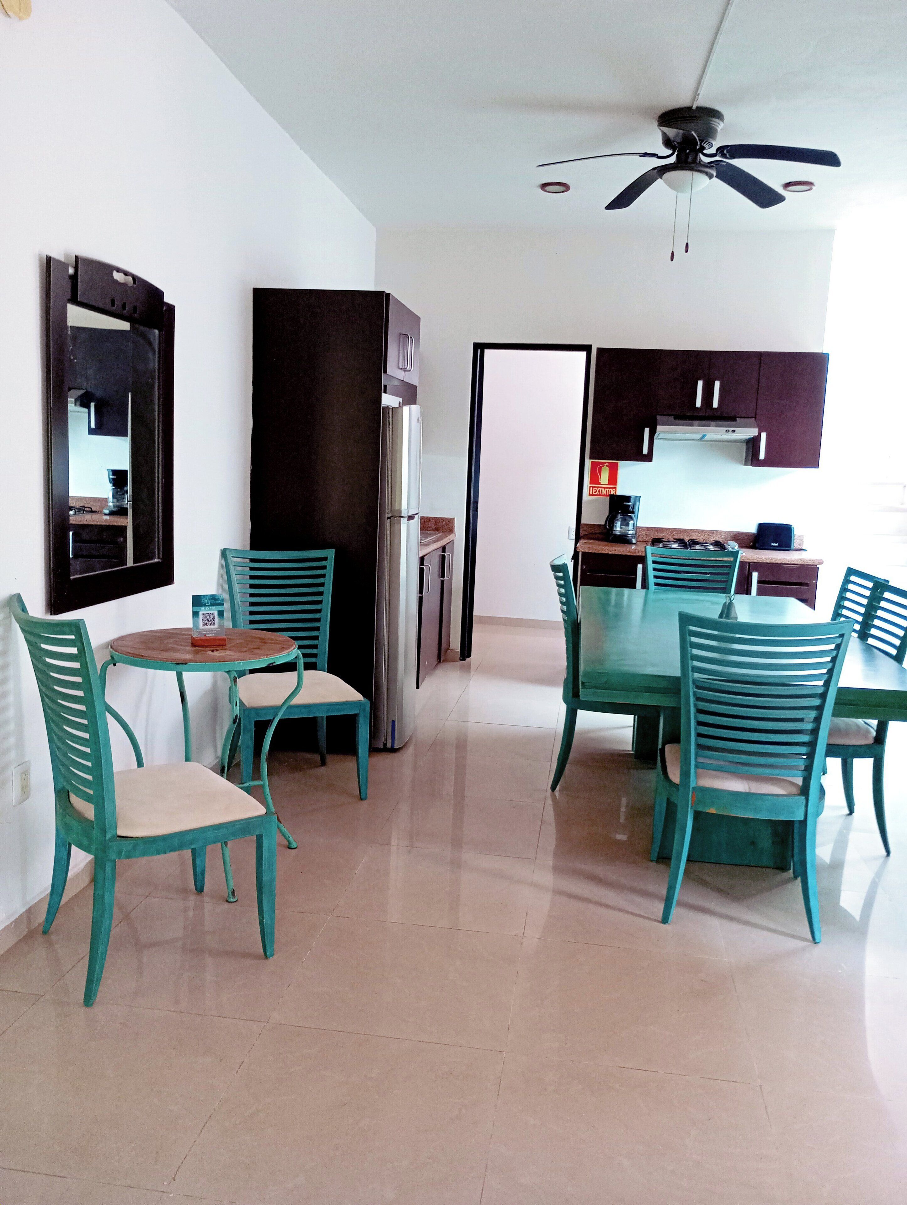 A compact kitchen with a refrigerator, a coffee maker, and a dining area with a table and chairs.