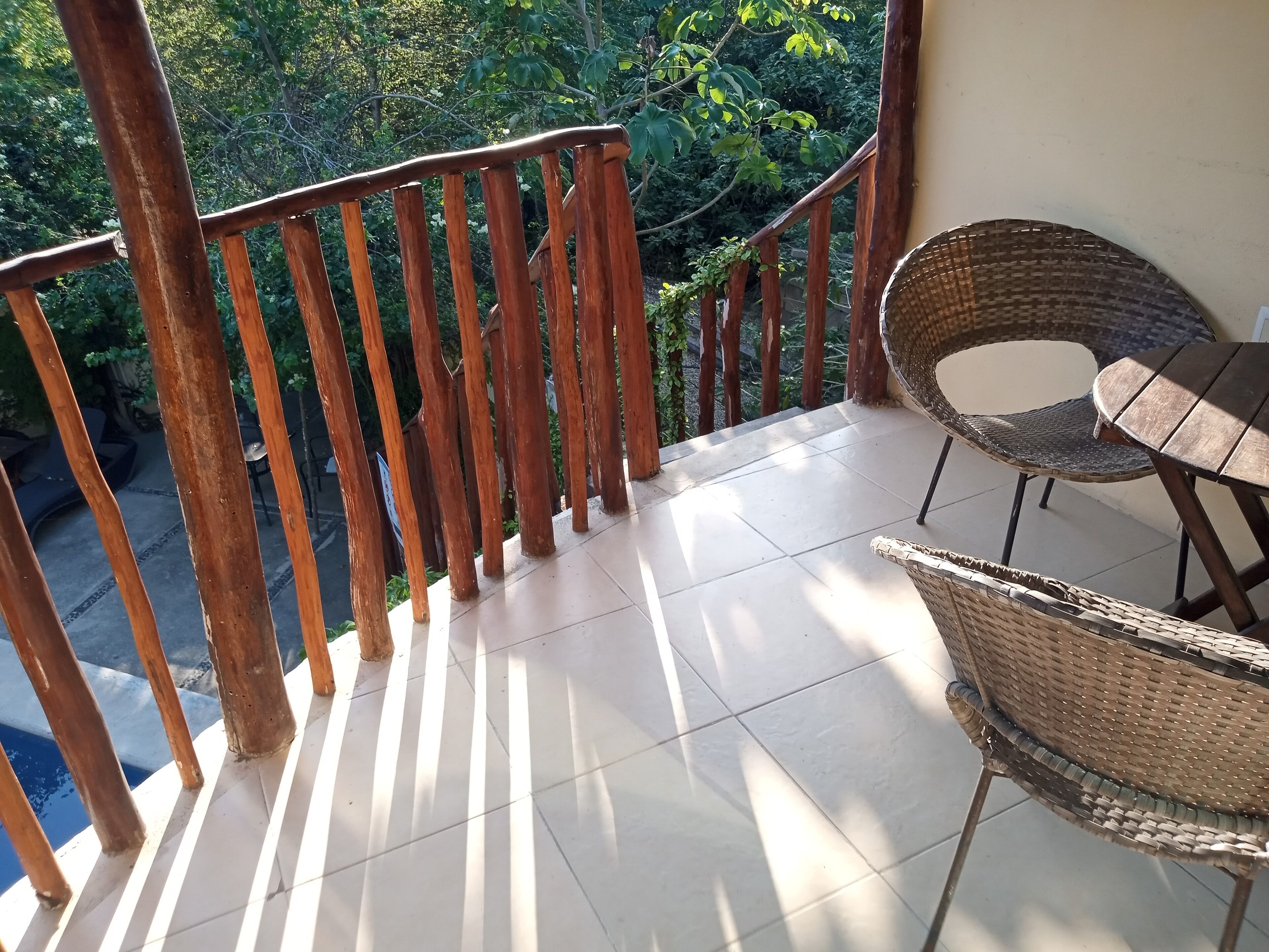 Un balcone con ringhiera in legno, un tavolino e sedie in vimini.