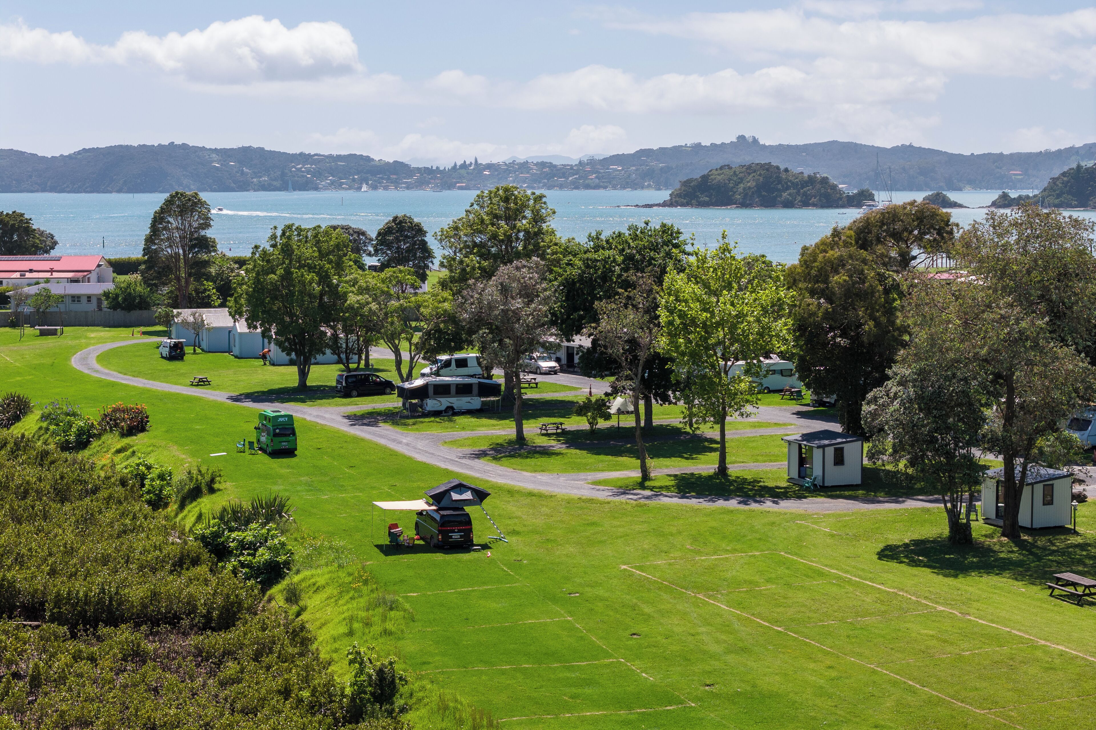 A campground with RVs, picnic tables, and a view of a lake and hills.