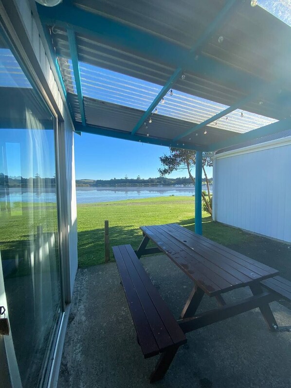 A covered outdoor area with a picnic table and a view of a lake.