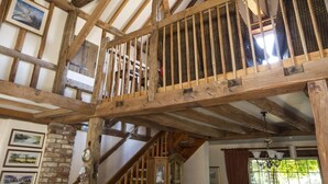 A room with exposed wooden beams, a staircase, and a view of the outdoors. - Magpies (Horsham)