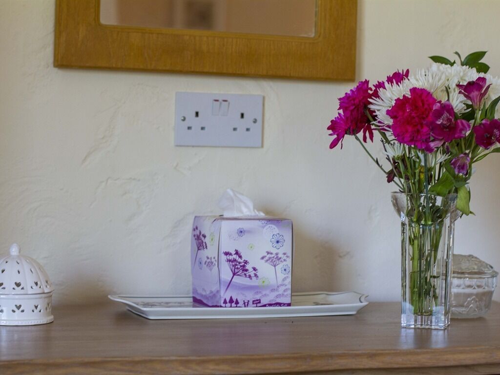 Ett bord med en servettask, en vas med blommor och en dekorativ prydnad på en träyta.