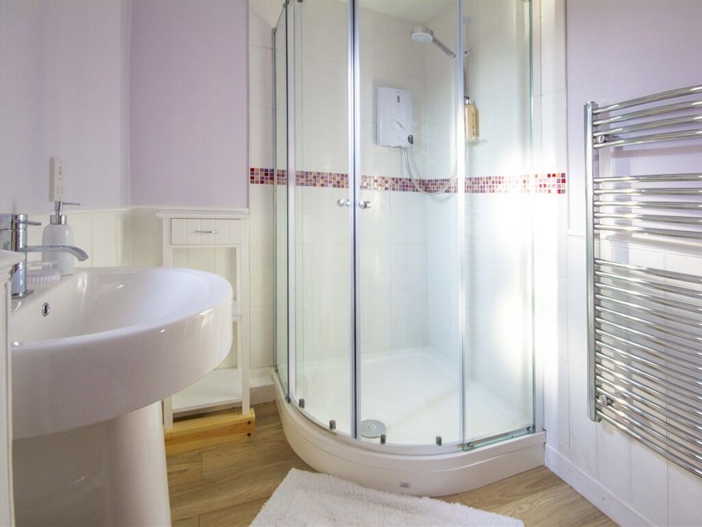 Un baño con ducha envuelta en vidrio, un lavabo blanco y un perchero para toallas.