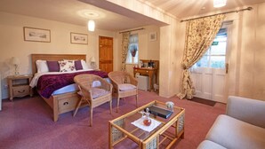 A bedroom with a bed, two wicker chairs, a small desk, a computer, and a window with curtains. - Magpies (Horsham)
