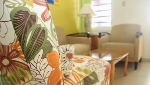 A living room with a floral sofa, a coffee table, and a lamp. - Alicia's Inn (Philipsburg)