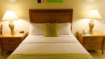 Una cama bien hecha con una colcha estampada, dos mesitas de noche con lámparas y una decoración de pared colorida.