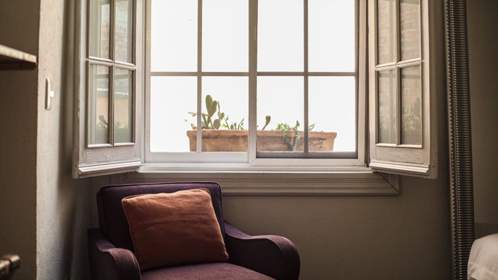 Una habitación con ventana, una silla y un radiador.