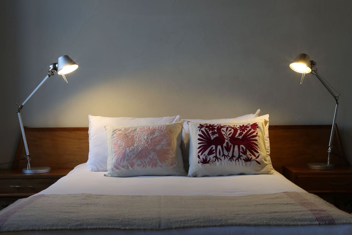 A neatly made bed with two pillows and two bedside lamps.