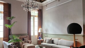 Una sala de estar con piso a cuadros, vigas de madera, un candelabro y un sofá.