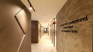 A modern hotel corridor with a reflective floor and a wall with a motivational quote. - Jeju Lux Hotel (Seogwipo)