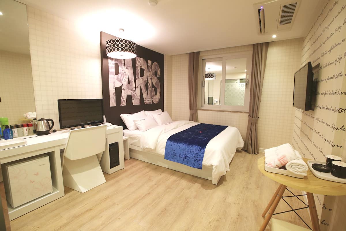 A hotel room with a bed, desk, and a TV.