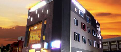 A multi-story building with a flat roof and a large glass facade on the ground floor.
