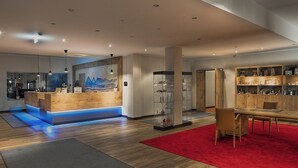 A modern hotel lobby with a reception desk, a dining area, and a display of decorative items.