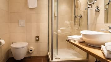 Een moderne badkamer met een douchecabine van glas, een wit toilet en een wastafelmeubel met een grote spiegel en wastafel.