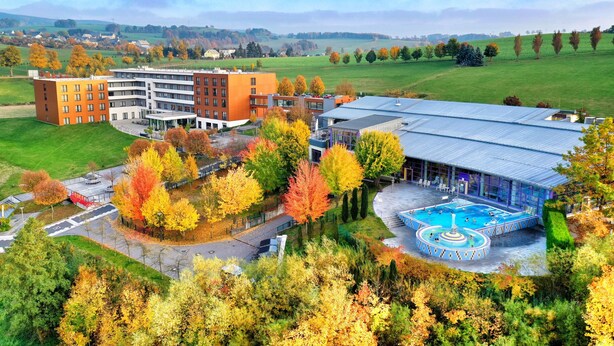 A modern building with a swimming pool and a parking lot.