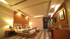 A hotel room with a large bed, bedside tables, a TV, and a wooden desk.