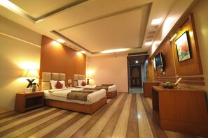 Una habitación de hotel con una cama grande, mesitas de noche, un televisor y un escritorio de madera.