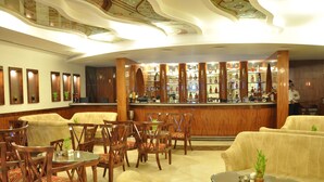 A bar area with wooden furniture, a bar counter, and shelves with bottles. - Hotel Babylon Inn (Raipur)
