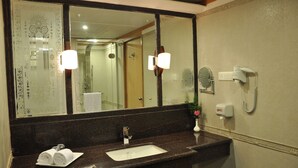 A bathroom with a large mirror, a sink, a towel rack, a hand dryer, and a soap dispenser.