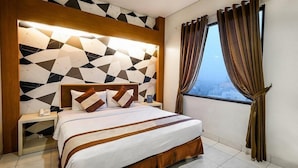 A modern hotel room with a geometric-patterned headboard, a neatly made bed with brown and white bedding, a bedside table with a phone, and a window with curtains. - Hotel 88 Mangga Besar VIII by WH (Jakarta)