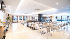 A spacious dining area with tables and chairs, a kitchen area with a sign reading "LIVE COOKING CORNER," and large windows offering a city view. - Hotel 88 Mangga Besar VIII by WH (Jakarta)