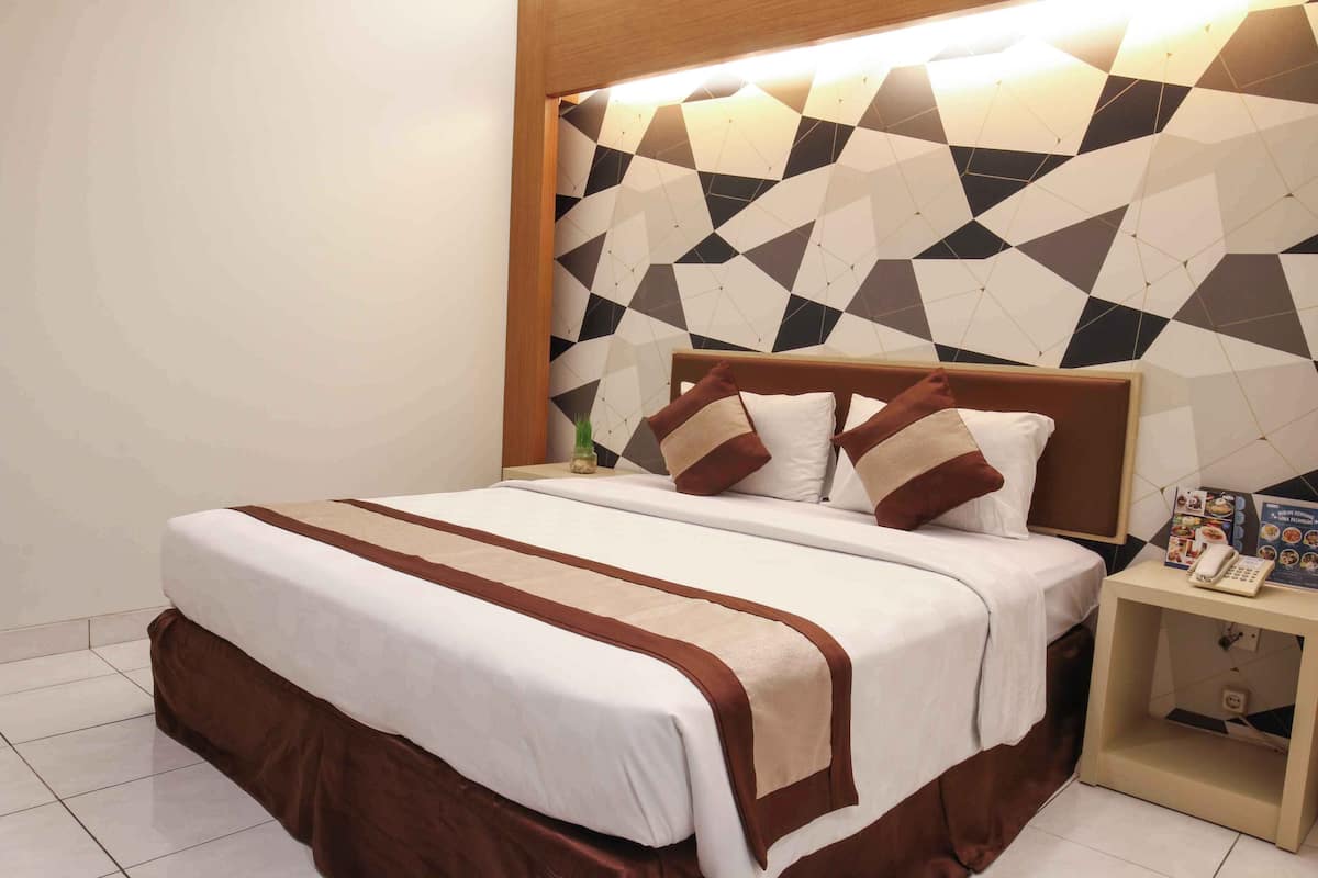 A neatly made bed with a brown and white bedspread, a wooden headboard, and a geometric-patterned wall behind it.
