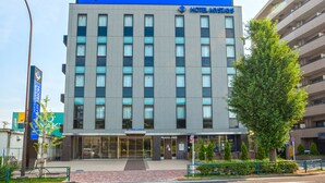 Un bâtiment moderne de l’hôtel Mystays, reconnaissable à son grand panneau bleu, à ses larges fenêtres et à l’entrée de son café-restaurant.
