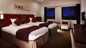 Une chambre d’hôtel avec deux lits, un bureau, une chaise et un téléviseur.