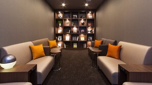 Un espace détente moderne avec deux canapés, de petites tables et une bibliothèque remplie de livres et d’objets décoratifs.