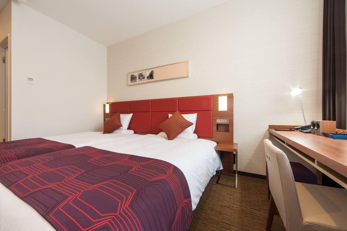 Quarto de hotel com uma cama grande, uma escrivaninha e uma cadeira.