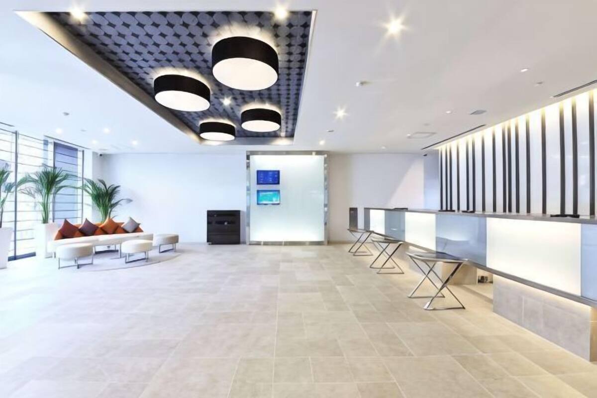 Um hall amplo com uma receção moderna, área de estar e uma grande tela.