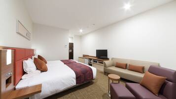 A hotel room with a bed, a sofa, a television, and a small table.