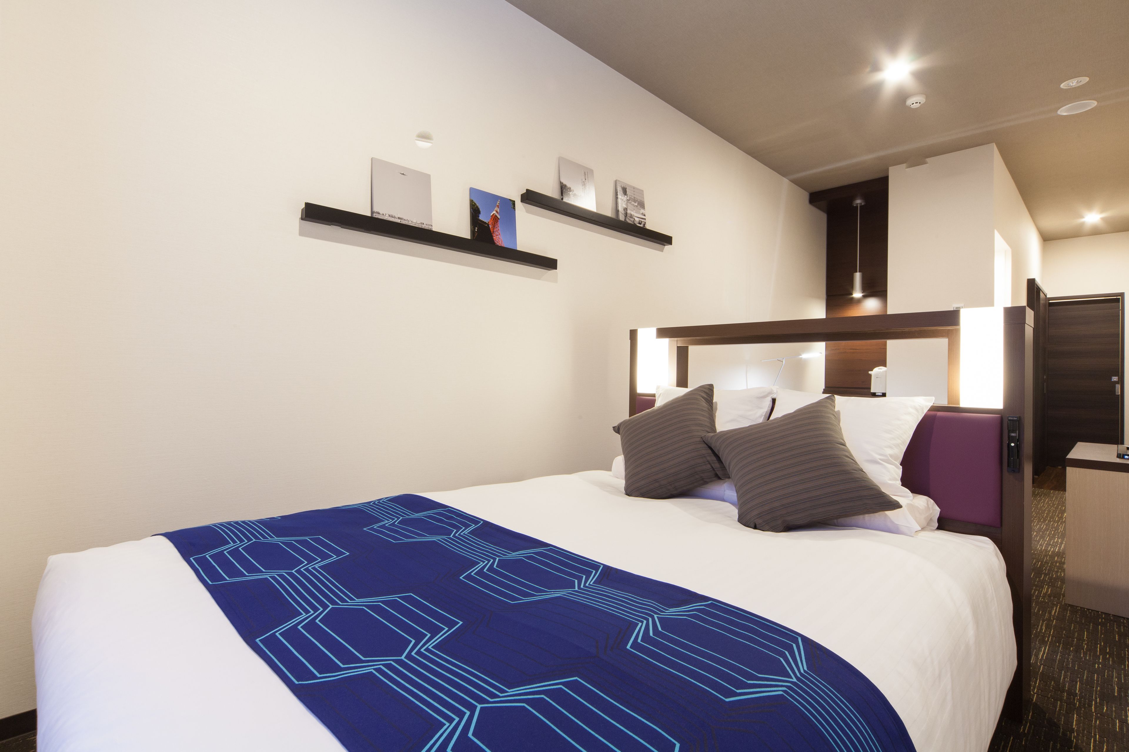 A hotel room with a bed, a nightstand, a desk, and a bathroom.