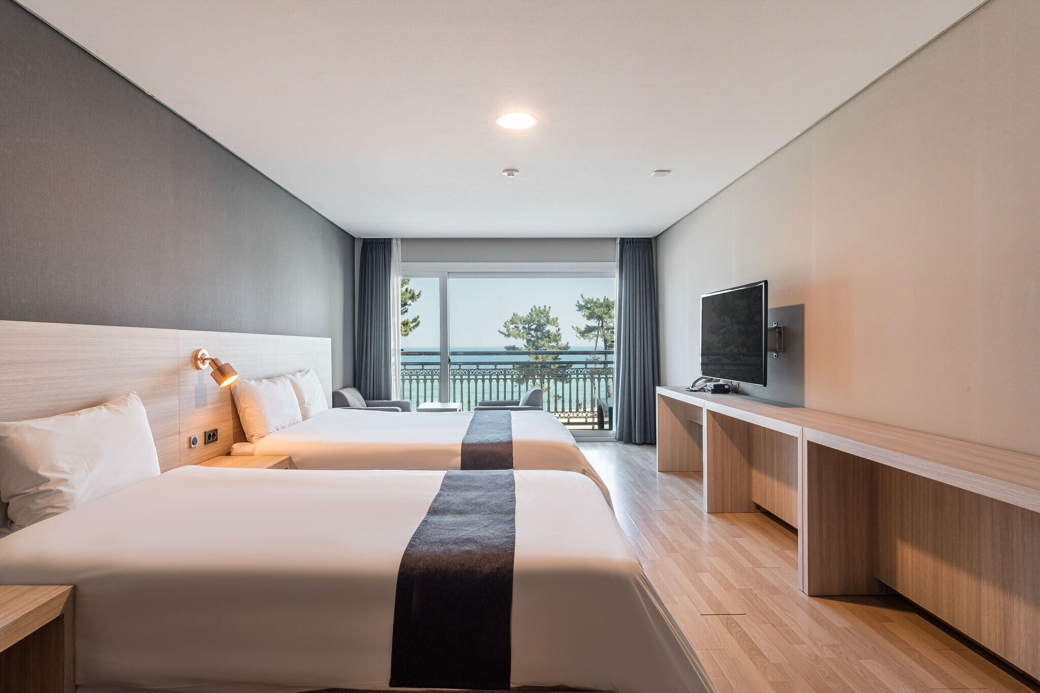 Une chambre d’hôtel avec deux lits, une télévision, un bureau et un balcon avec vue.